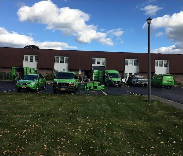 Green SERVPRO fleet vehicles parked at a job site with equipment removed