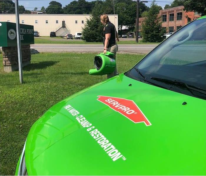 an employee carrying water damage equipment by a SERVPRO van