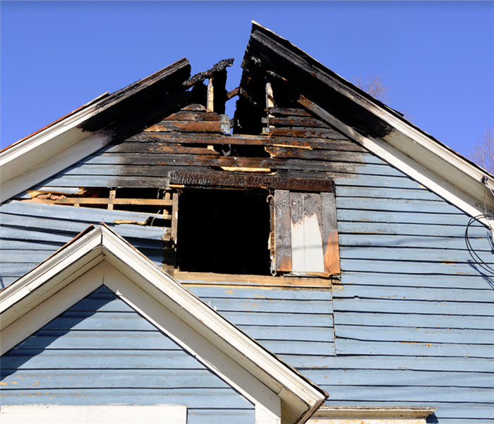 a fire damaged house with a burned roof