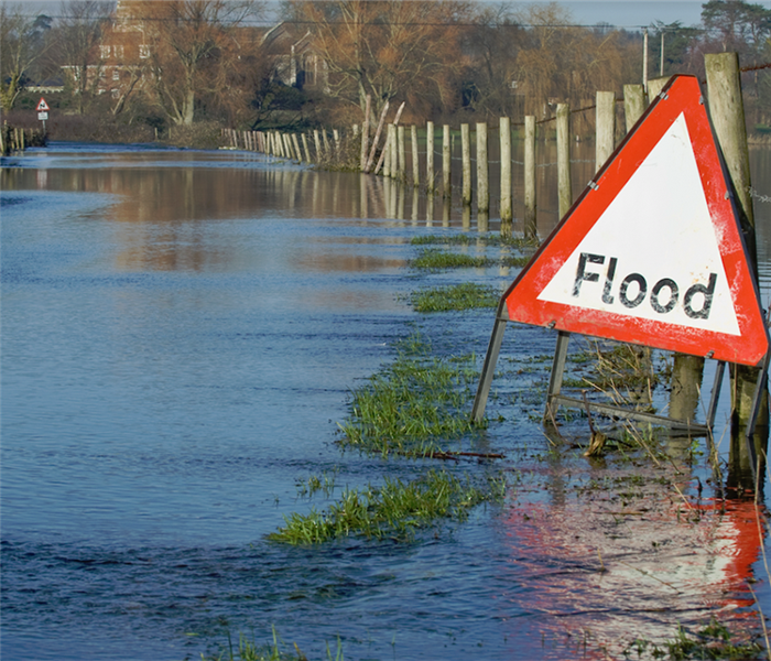 a flooded street with a partially submerged sign that says flood